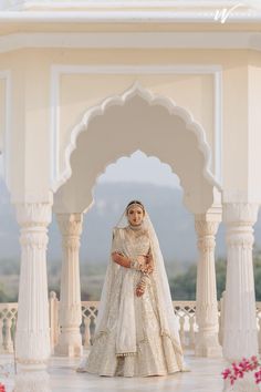 a woman standing in front of a white gazebo wearing a bridal gown and veil