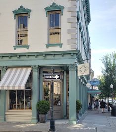 a store front with awnings and people walking on the sidewalk