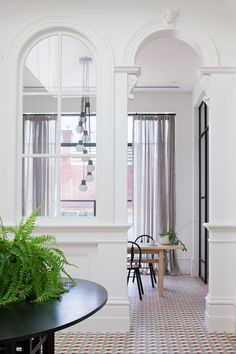 a living room filled with furniture next to a window and potted plant on top of a table