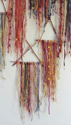 there is a wall hanging made out of different colored yarns and sticks, with the string attached to it