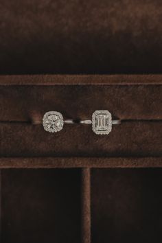 two diamond earrings sitting on top of a wooden box