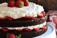 a chocolate cake with whipped cream and strawberries on top is sitting on a table