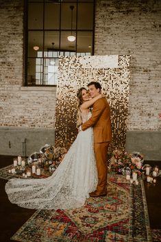 a bride and groom embrace in front of a backdrop with candles at their wedding reception