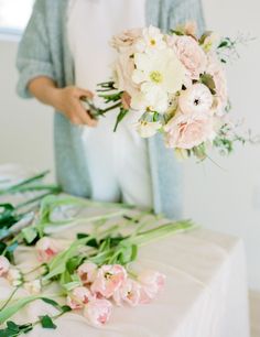 a woman holding a bouquet of flowers on top of a table