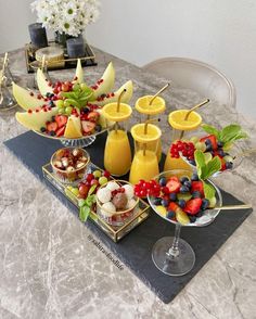 a table topped with fruit and drinks on top of a counter next to a vase filled with flowers