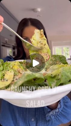 a woman holding a plate with salad on it