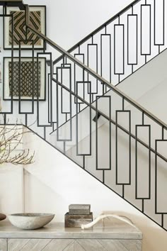 a white and black stair case next to a table with a bowl on top of it