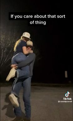 a man and woman hugging each other in the middle of an empty parking lot at night