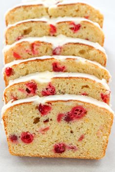 several slices of cake with white icing and raspberries