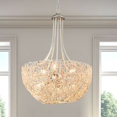 a white chandelier hanging from a ceiling in a room with windows and furniture