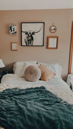 a bed with two pillows and pictures on the wall above it, along with other decor