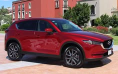 a red mazda cx - 5 parked in front of a building