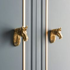 two brass horse head knobs on the front of a blue door with gold handles