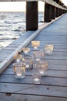 candles are lined up on a wooden dock