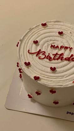 a birthday cake with white frosting and red hearts