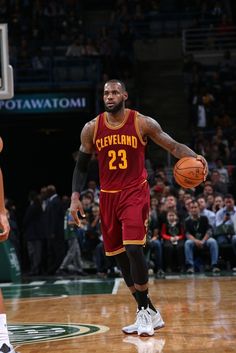 a basketball player dribbling the ball while standing in front of an audience at a game