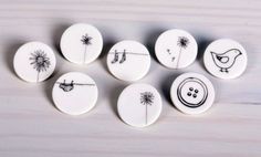 six buttons with different designs on them sitting on a wooden surface in front of a white background