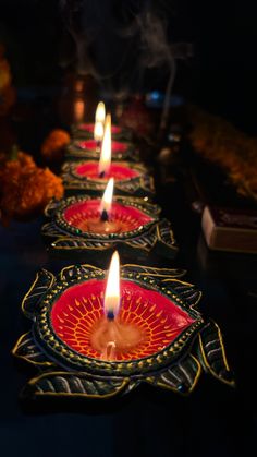 candles are lit in the middle of a long line of plates with designs on them