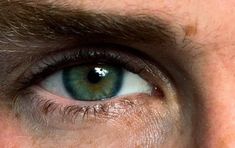 a man's green eyes are seen in this image