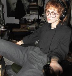 a person sitting in a chair with headphones on their ears and holding a remote