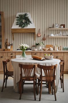 a kitchen with wooden cabinets and white table cloth on the dining room table surrounded by chairs