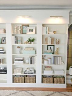 a living room filled with lots of white bookshelves and wicker baskets on top of them