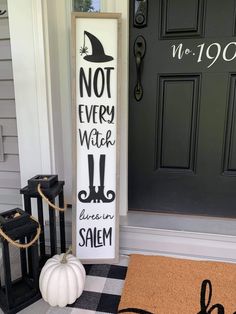 a wooden sign that says not every witch is in salem on the front porch next to a black and white door