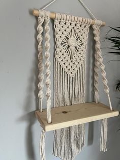 a white macrame hanging on a wall next to a potted plant