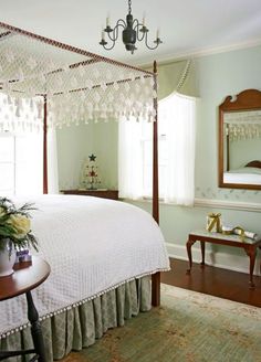 a white bed sitting in a bedroom next to a table with flowers on top of it