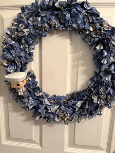 a wreath made out of blue jeans with a sailor doll on it