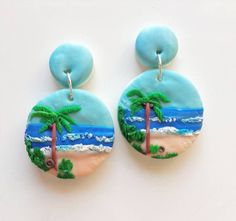 two earrings with palm trees on the beach