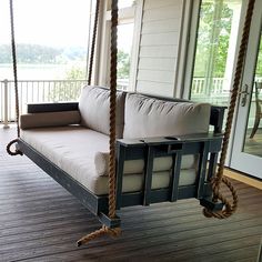 a porch swing bed with pillows on the front and back sides hanging from it's posts