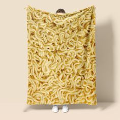 a person standing in front of a large pile of noodles wrapped in a yellow blanket