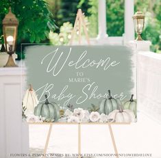 a welcome sign for a baby shower with pumpkins and flowers in front of it