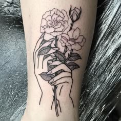 a black and white photo of a person holding flowers on their arm with the word love written