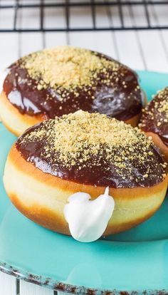 three chocolate covered donuts on a blue plate