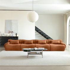 an orange couch sitting in the middle of a living room next to a stair case