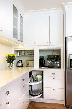 a kitchen with white cupboards and stainless steel refrigerator freezer next to wooden flooring