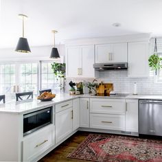 a kitchen with white cabinets and gold trim on the counter tops, along with a rug