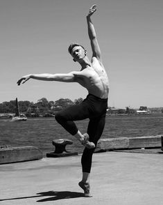 a shirtless man doing a dance move near the water