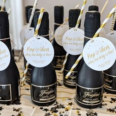 there are many black bottles with gold and white paper straws in them on the table