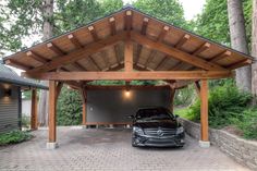 a car is parked in the driveway under a wooden structure with an attached carport