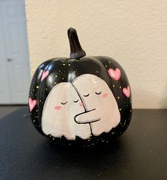 a black and white pumpkin with two faces painted on it's face, sitting on a table