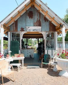 an old building with lots of furniture and flowers in the front yard, including two lawn chairs