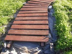 a wooden walkway in the middle of some grass