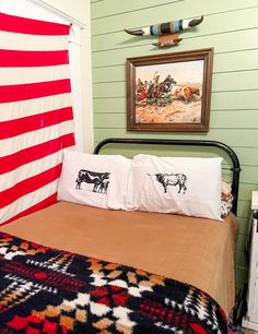 a bed with two pillows on top of it and an american flag hanging over the headboard