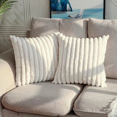 two white pillows sitting on top of a couch