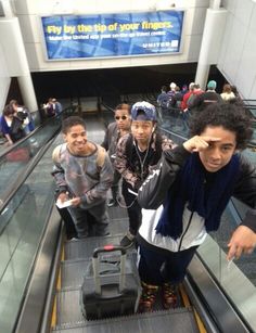 several people are standing on an escalator and one person is pointing at the camera