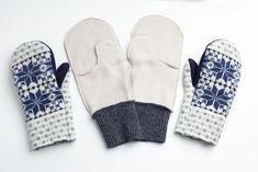 two mittens sitting next to each other on top of a white table with blue and white designs