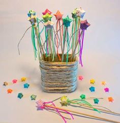 a basket filled with lots of colorful paper stars and pinstripe sticks on top of a white surface